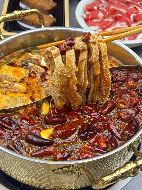 Sichuan hot pot — chopsticks lift a piece of beef tripe from the bubbling spicy red broth
