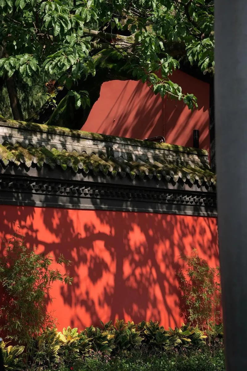 Red walls and mossy tiled roofs with tree shadows at Wuhou Shrine in Chengdu