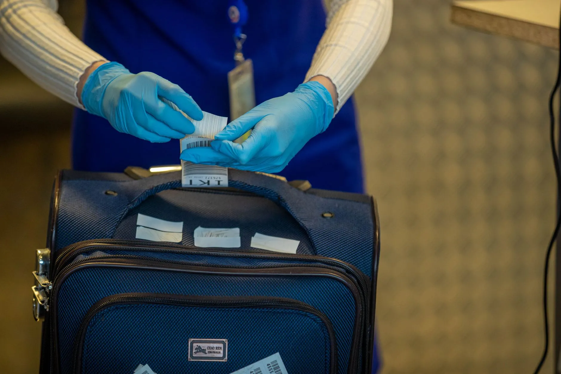 A gloved hand checking a baggage tag at an airport security checkpoint