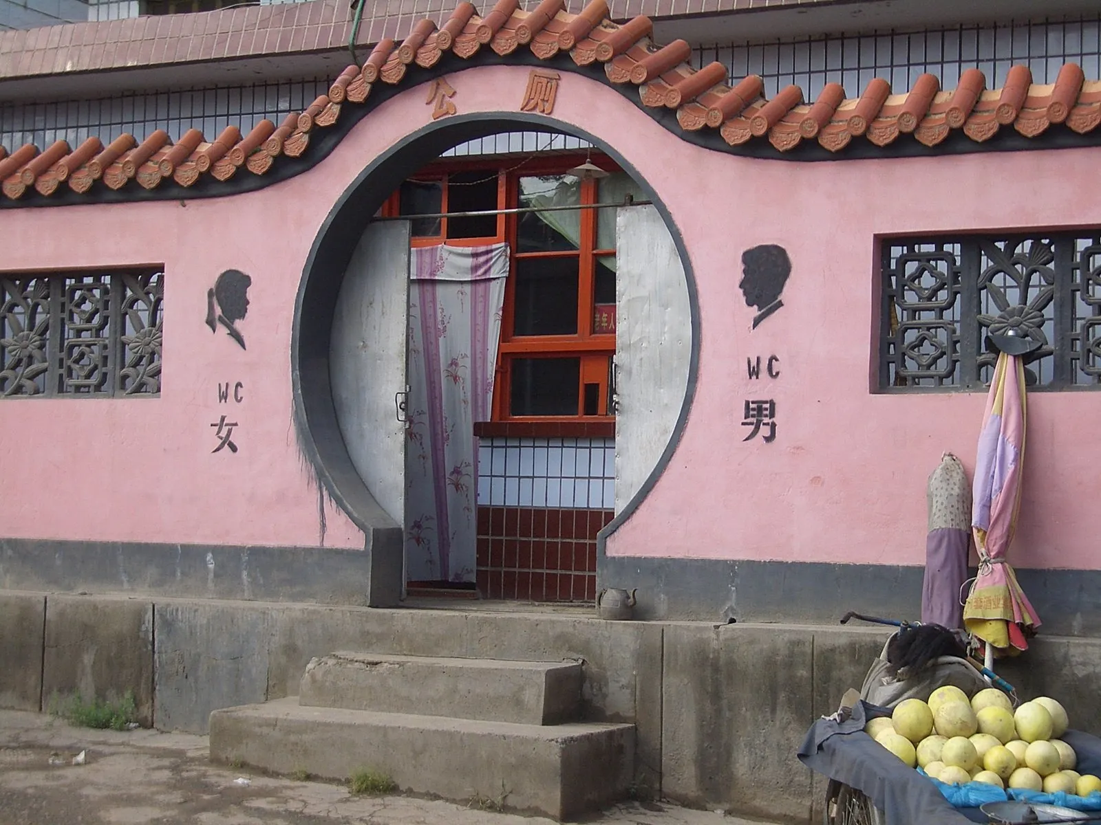 A neighbourhood public toilet with a moon-gate entrance and separate men's and women's sides on Xiguan Road in Linxia, Gansu