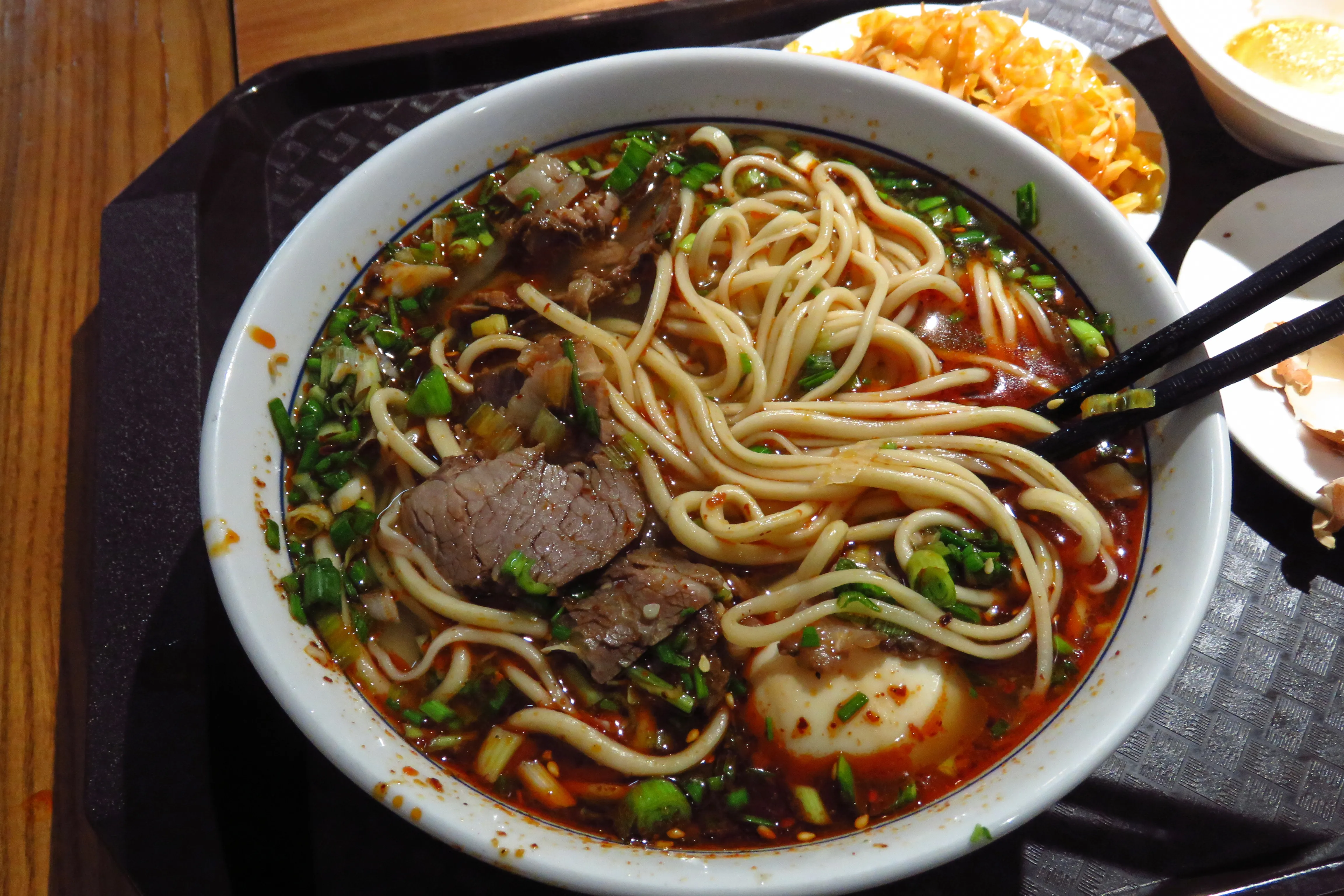 Authentic Lanzhou beef noodle soup — clear broth, hand-pulled noodles, sliced beef, red chili oil and fresh cilantro